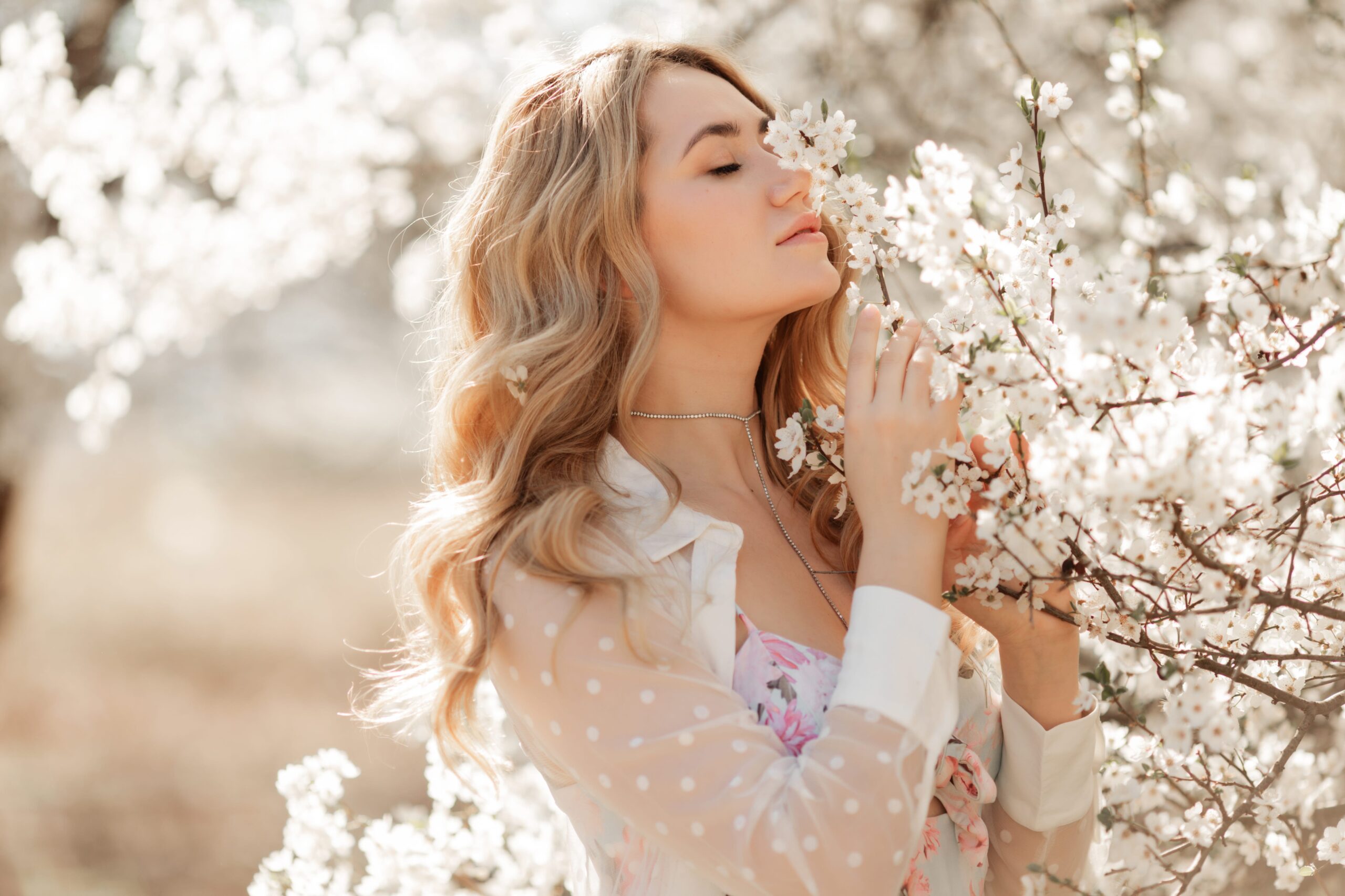 桜の花に顔を寄せる女性と指輪とピアスの写真